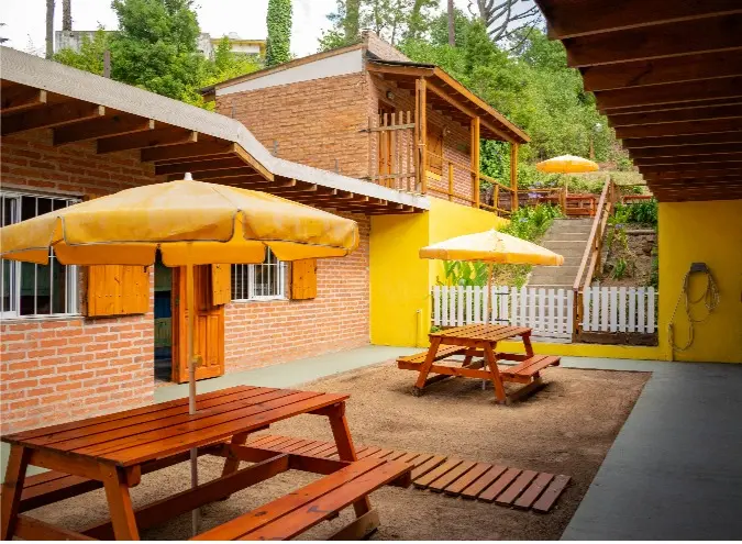 Patio con sombrillas amarillas y mesas de madera