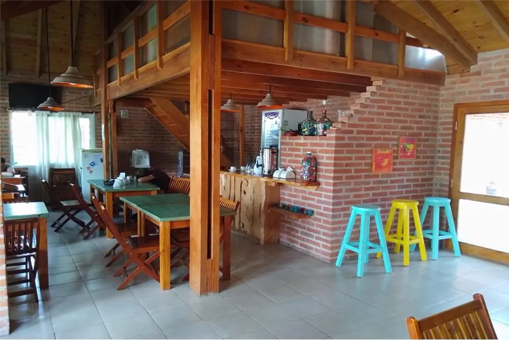 Salón con barra, banquetas de colores y escalera de madera